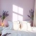 Cozy bedroom with soft lavender walls and white bedding, accented by lavender flowers.