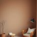 Minimalist bedroom corner with warm taupe walls, a wooden chair, and a side table.